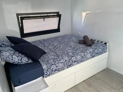 a small bedroom with a bed with blue and white sheets at Houseboat Cádiz El Puerto - Casa Flotante in El Puerto de Santa María