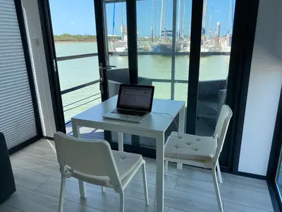 a laptop computer sitting on a white table with two chairs at Houseboat Cádiz El Puerto - Casa Flotante in El Puerto de Santa María