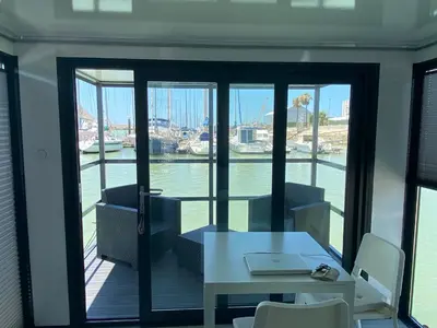 a room with a table and chairs and a view of the water at Houseboat Cádiz El Puerto - Casa Flotante in El Puerto de Santa María