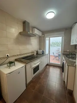 a kitchen with white appliances and a view of a patio at Gades de la Caleta con Terraza Grupo AC Gestion in Cádiz