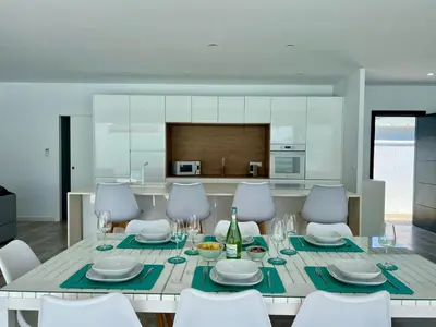 a dining room with a table and chairs and a kitchen at Casa El Azul in Chiclana de la Frontera