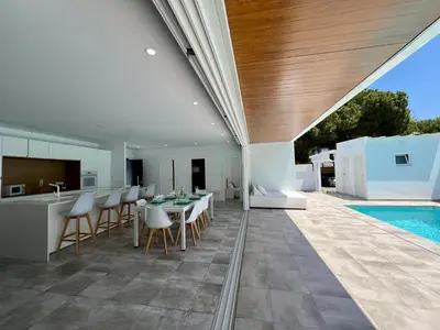 an outdoor kitchen and dining area of a house with a pool at Casa El Azul in Chiclana de la Frontera
