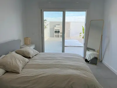a large bed in a bedroom with a large window at Chalet El Eden in Chiclana de la Frontera