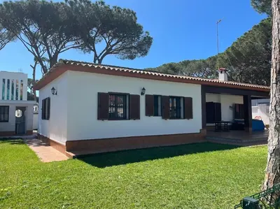 a small white house with a green yard at Chalet Urb Doña Violeta 500m Mar in Chiclana de la Frontera