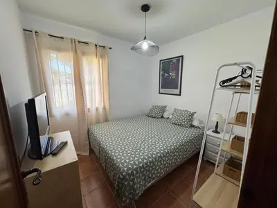 a small bedroom with a bed and a shelf at Chalet Urb Doña Violeta 500m Mar in Chiclana de la Frontera