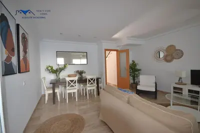 a living room with a couch and a dining room at Adosado Familiar con Piscina y Terraza in Cádiz
