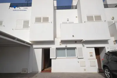 a white building with a car parked in front of it at Adosado Familiar con Piscina y Terraza in Cádiz