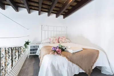 a white bedroom with a bed with flowers on it at Casa Antonia I in Jerez de la Frontera