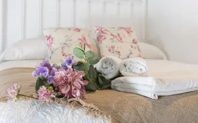 a bed with towels and a bouquet of flowers on it at Casa Antonia I in Jerez de la Frontera