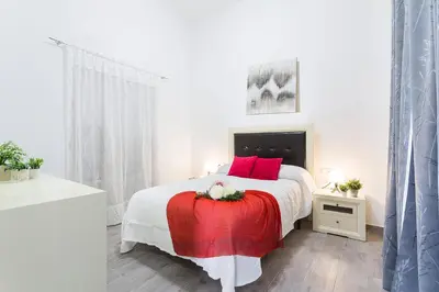 a white bedroom with a large bed with red pillows at Casa Antonia I in Jerez de la Frontera
