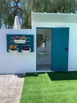 a house with a blue bench with two flower pots on it at LOS ANTONIOS Loft Rural Chipiona in Cádiz