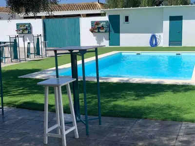 a table and two stools in front of a pool at LOS ANTONIOS Loft Rural Chipiona in Cádiz