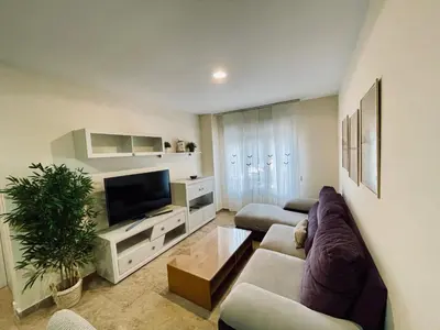 a living room with a couch and a tv at Apartamento La Porteña, 200 ms de playa Victoria in Cádiz