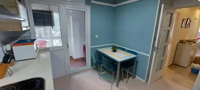 a kitchen with a blue wall and a small table at Apartamento La Porteña, 200 ms de playa Victoria in Cádiz