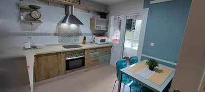 a kitchen with a table and a stove top oven at Apartamento La Porteña, 200 ms de playa Victoria in Cádiz