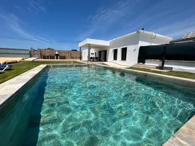 a swimming pool in front of a house at Chalet Namasté in Conil de la Frontera