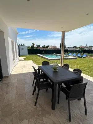 a black table and chairs on a patio with a pool at Chalet Namasté in Conil de la Frontera