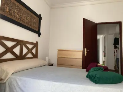 a bedroom with a bed and a wooden headboard at Casa Carmela - PÓPULO in Cádiz
