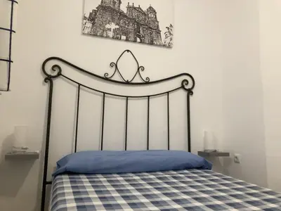 a bed in a bedroom with a black and white bedspread at Casa Carmela - PÓPULO in Cádiz