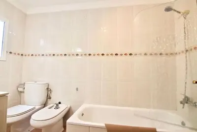 a white bathroom with a toilet and a bath tub at Casa Carmela - PÓPULO in Cádiz
