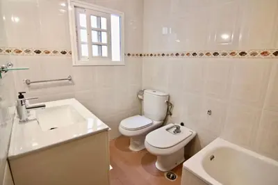 a white bathroom with a toilet and a sink at Casa Carmela - PÓPULO in Cádiz