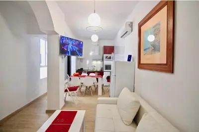a living room with a white couch and a kitchen at Casa Carmela - PÓPULO in Cádiz