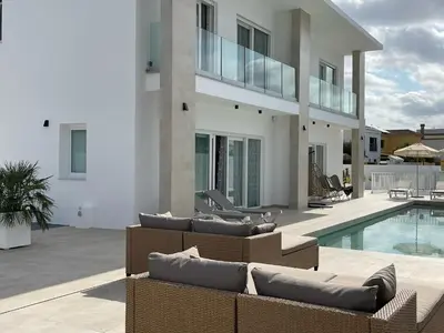 a large white house with a swimming pool and furniture at Casa Bahía de Cádiz in Conil de la Frontera