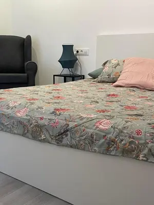 a bed with a flowered comforter and a chair at Casa Bahía de Cádiz in Conil de la Frontera