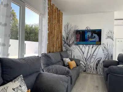 a living room with a couch and a tv on a wall at Casa Bahía de Cádiz in Conil de la Frontera