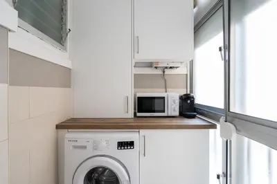 a small kitchen with a washing machine and a microwave at Apartoyou - Pinar Lux in El Puerto de Santa María