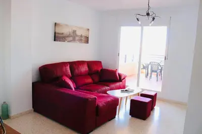 a living room with a red couch and a table at Albatros Sanlucar in Sanlúcar de Barrameda