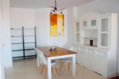 a dining room with a white table and chairs at Albatros Sanlucar in Sanlúcar de Barrameda