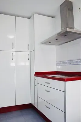a kitchen with white cabinets and a red counter top at Albatros Sanlucar in Sanlúcar de Barrameda