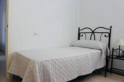 a bedroom with a bed with a white comforter at Albatros Sanlucar in Sanlúcar de Barrameda