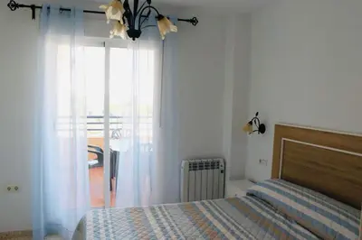 a bedroom with a bed and a glass door with a window at Albatros Sanlucar in Sanlúcar de Barrameda