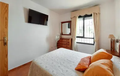 a bedroom with a bed and a television on the wall at Lovely Apartment In Chiclana De La Front in Poblado de Sancti Petri