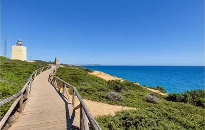 a wooden boardwalk leading to a lighthouse and the ocean at Lovely Apartment In Chiclana De La Front in Poblado de Sancti Petri