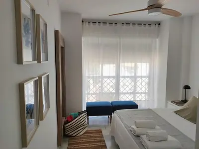 a white bedroom with a bed and a window at Casa Bermeo in Sanlúcar de Barrameda
