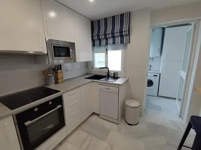a white kitchen with a sink and a stove at Casa Bermeo in Sanlúcar de Barrameda