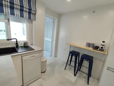 a kitchen with a sink and two blue stools at Casa Bermeo in Sanlúcar de Barrameda