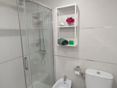 a white bathroom with a shower and a toilet at Casa Bermeo in Sanlúcar de Barrameda