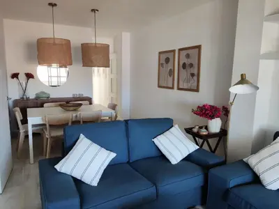 a living room with a blue couch and a table at Casa Bermeo in Sanlúcar de Barrameda