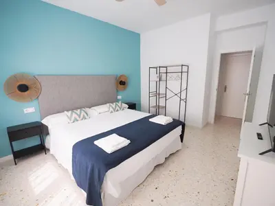a bedroom with a large bed with a blue wall at Sanlúcar Urban Apartment in Sanlúcar de Barrameda