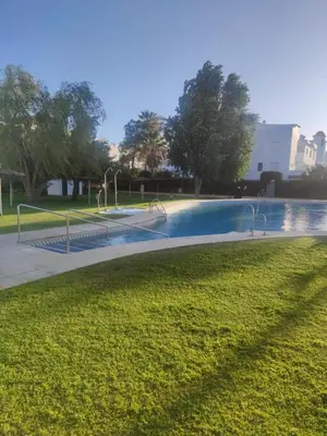 a swimming pool in a park with trees and grass at VILLA MARISMAS DE LA ALMADRABA in Chiclana de la Frontera