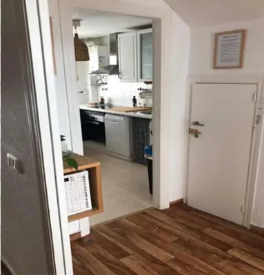 a kitchen with white cabinets and a wooden floor at VILLA MARISMAS DE LA ALMADRABA in Chiclana de la Frontera