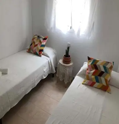 a room with two beds and a table and a window at VILLA MARISMAS DE LA ALMADRABA in Chiclana de la Frontera
