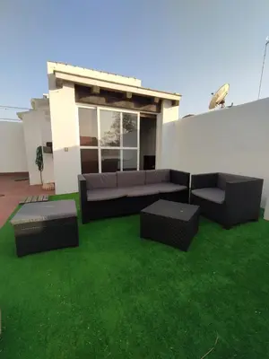a patio with a couch and tables on the grass at APARTAMENTO SEGUNDA PLANTA in Chiclana de la Frontera