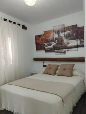 a bedroom with a bed with four pictures on the wall at Apartamento EG17 in Arcos de la Frontera