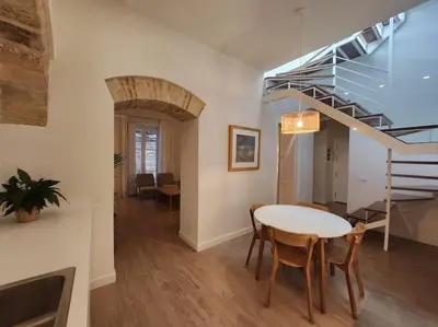 a dining room with a table and a spiral staircase at Apartamento Ancha 3 in Sanlúcar de Barrameda