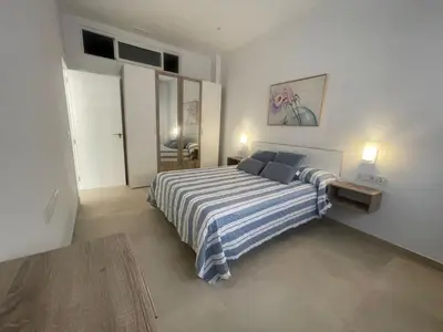 a bedroom with a bed with blue and white striped sheets at Dani Home in Cádiz